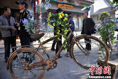 2月6日，在云南楚雄彝人古镇的街道上，3辆废旧自行车经过艺术家的巧手加工，变成新潮艺术品，吸引来往游客驻足观赏。