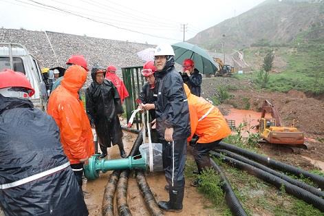 图一为中州铝业保障中心员工冒雨在现场搬运潜水泵设备，以应对未来几天更加严峻的汛情。